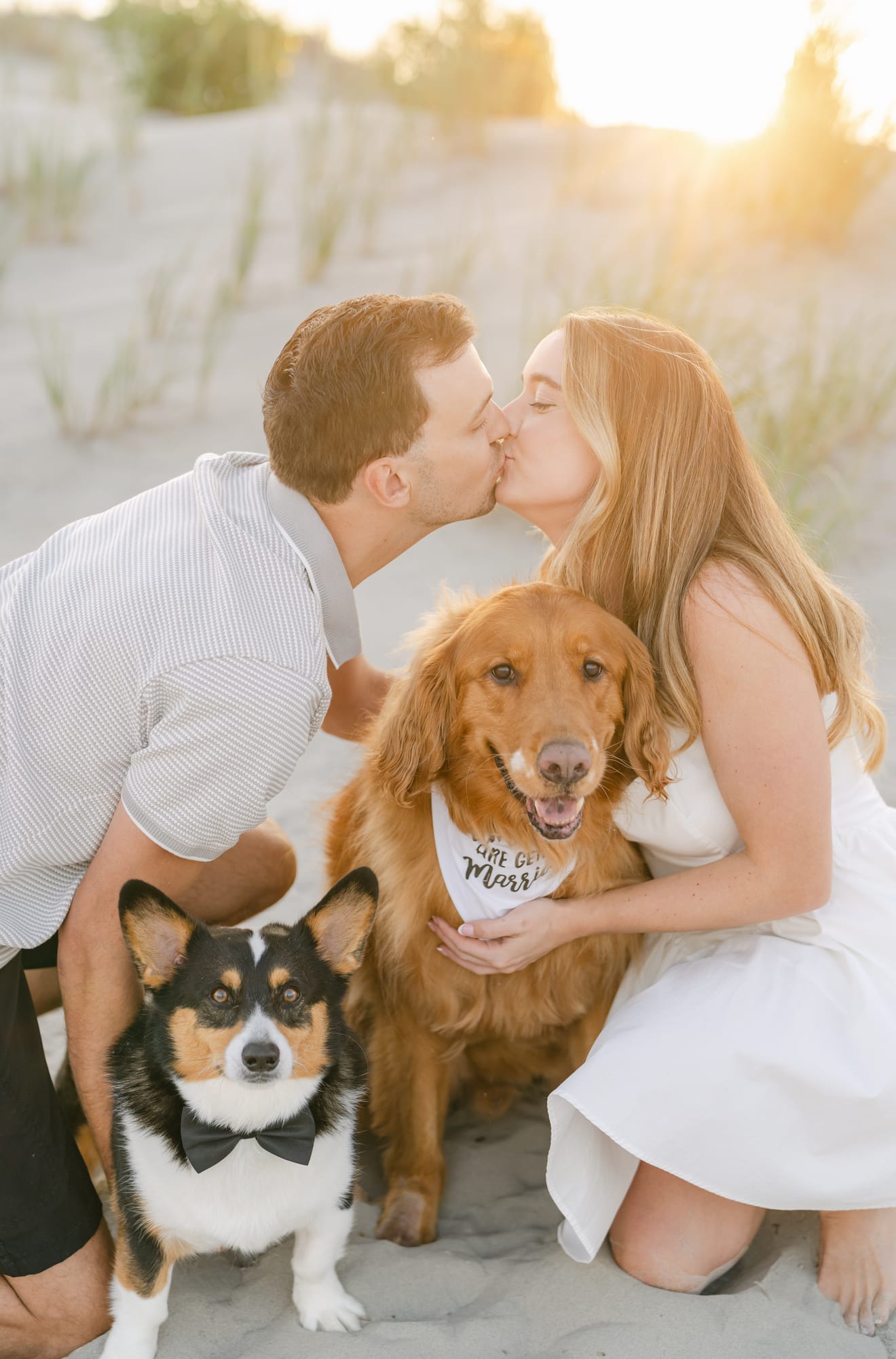 John and Samantha kissing their golden retriever on the beach