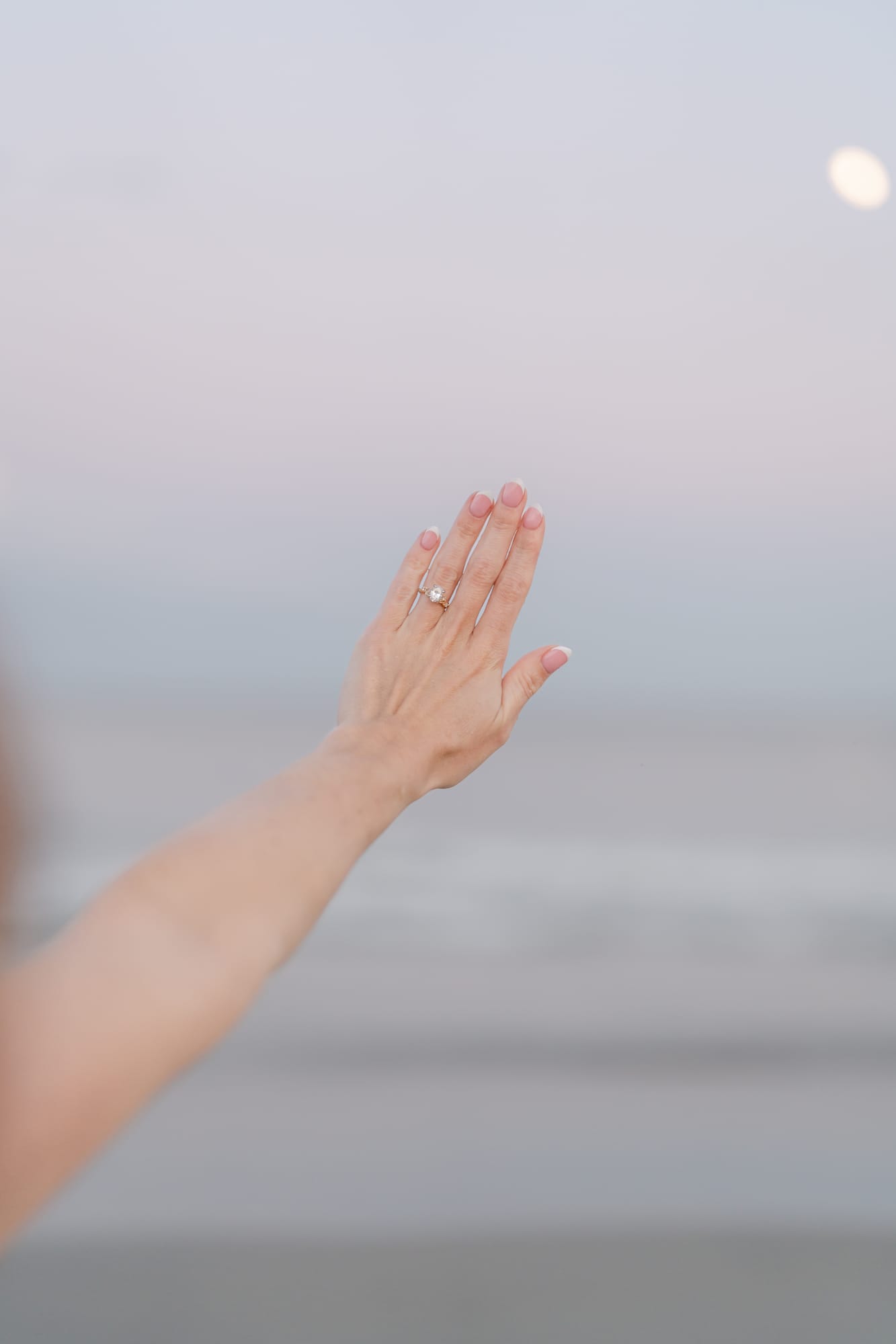 Samantha's engagement ring against a pastel sky